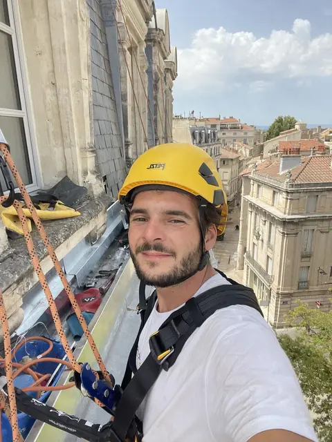 Lucas encordé sur une corniche au-dessus de la ville
